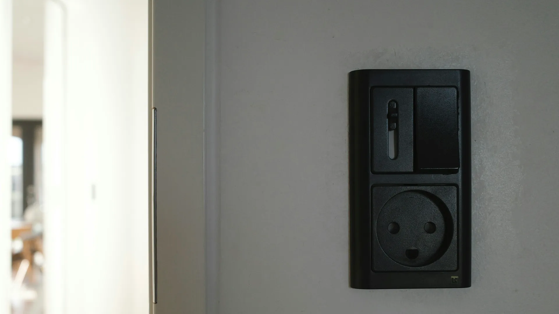 Zwart stopcontact met schakelaar op een strak afgewerkte wand in een woonkamer